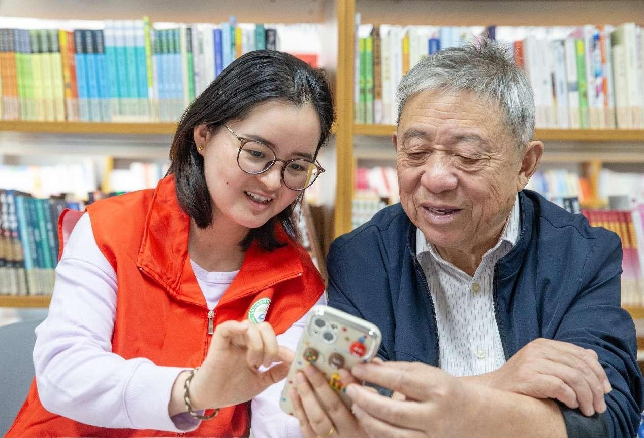 Seorang sukarelawan mengarahkan seorang warga emas menggunakan telefon pintar semasa bengkel di kejiranan Xianfeng, Nantong, provinsi Jiangsu, di timur China. (People’s Daily Online/Zhai Huiyong)